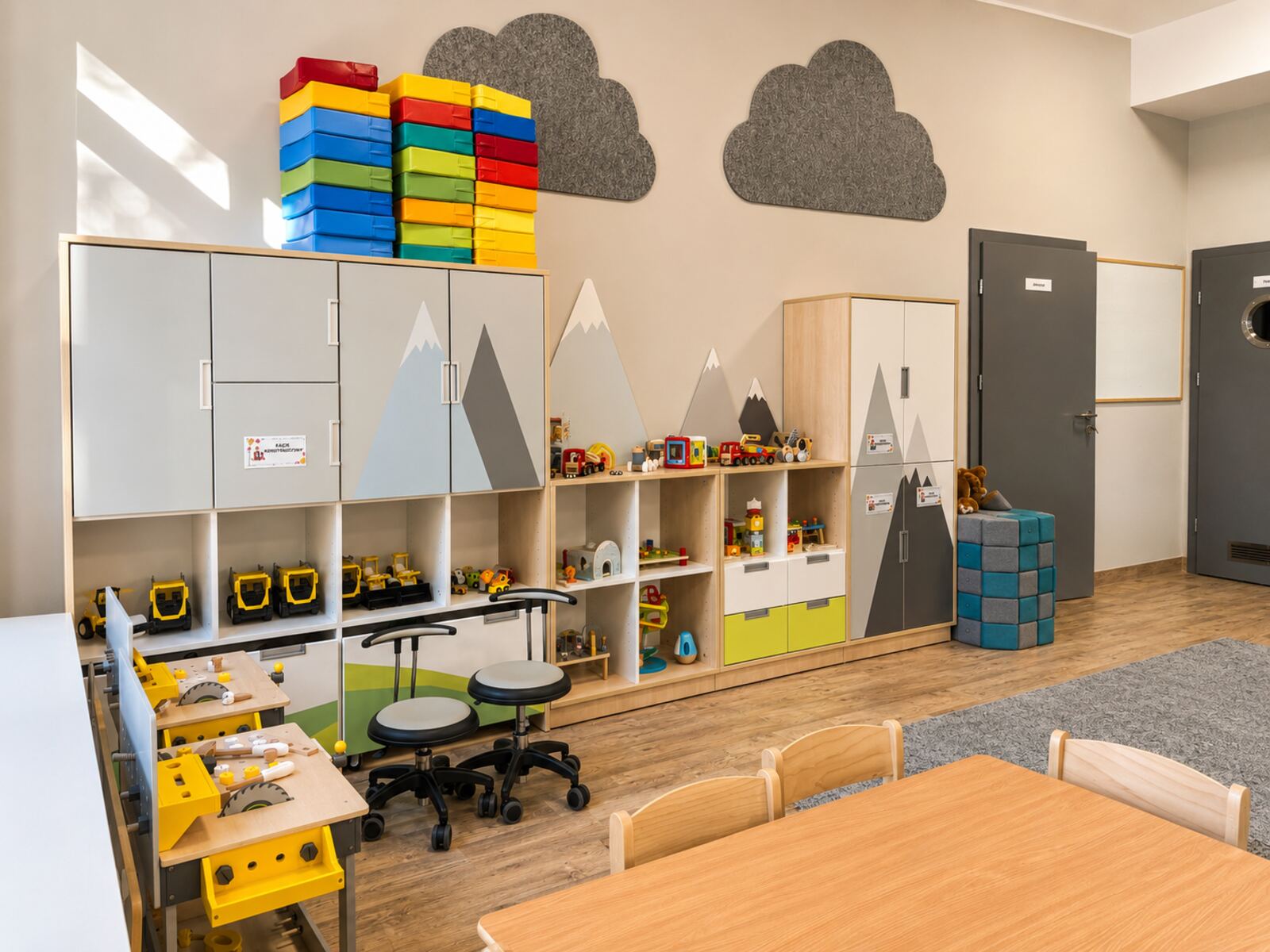 Sala z szafkami ozdobionymi motywem gór i stolikami dla dzieci